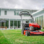 lawn mower sits in grass outside residential home
